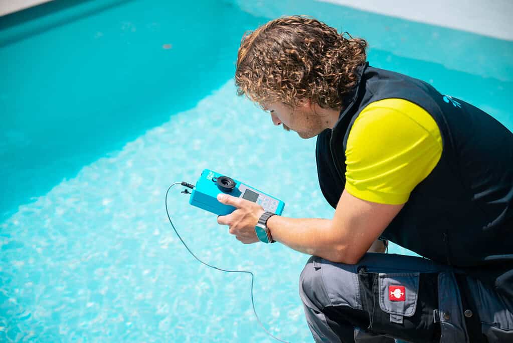 Ein Pooltechniker prüft die Wasserqualität eines Pools für eine Poolsanierung.
