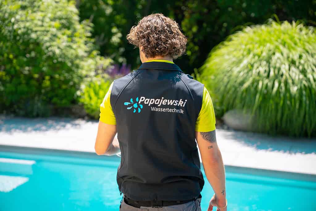 Ein Pooltechniker von Papajewski begutachtet einen Außenpool vor Beginn der Schwimmbadsanierung.