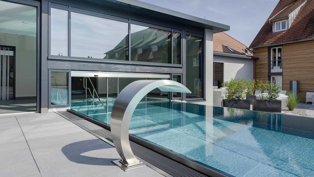 Nahaufnahme des Infinity Pool Zugangs. Im Fokus steht eine Wasserfontäne aus Metall.