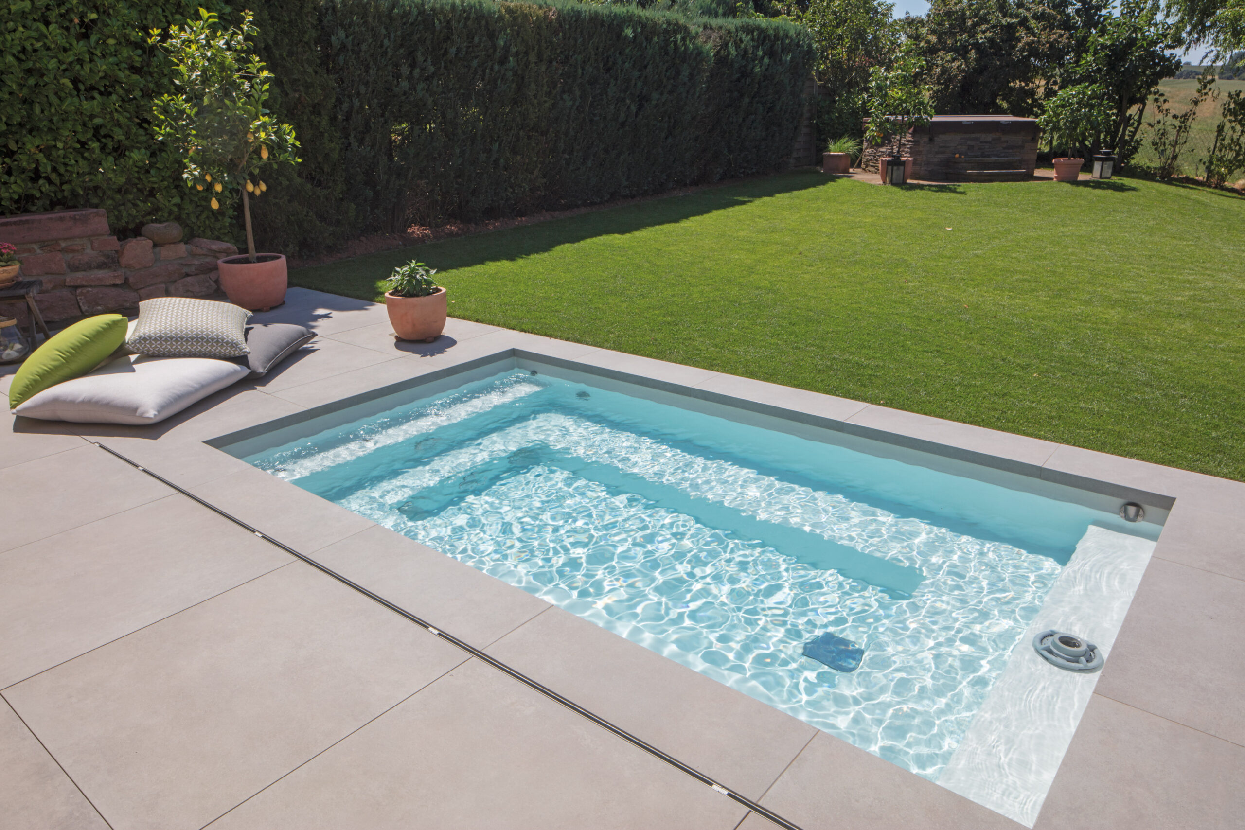 Mini-Pool C-Side 37 in einem Garten mit Terrasse und Steinplatten, vertrieben vom Würzburger Poolbauer Papajewski.