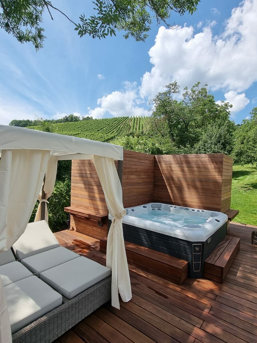 In ein Holzgebilde eingelassener Whirlpool neben gepolsterten Liegen an einem Weinberg