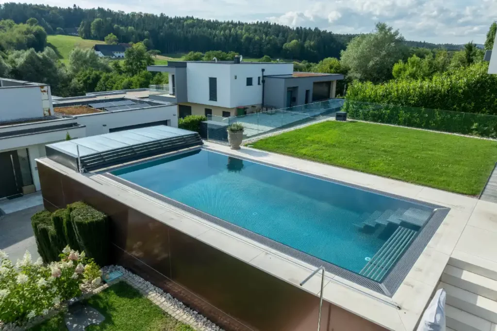 Moderner Edelstahlpool von Papajewski Poolbau aus Würzburg neben einer Terrasse mit Rasen in einem Neubaugebiet.