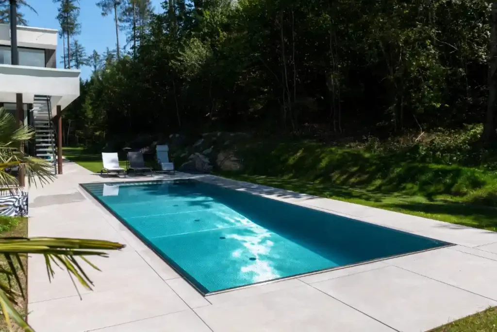 Terrasse mit Liegestühlen, angrenzendem Waldstück und modernem Edelstahlpool in der Nähe von Würzburg.