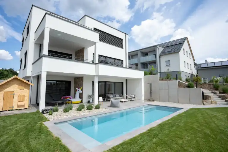 Skimmerpool im Garten eines modernen weißen Wohnhauses in der Nähe von Schweinfurt mit Unterflurrollo.
