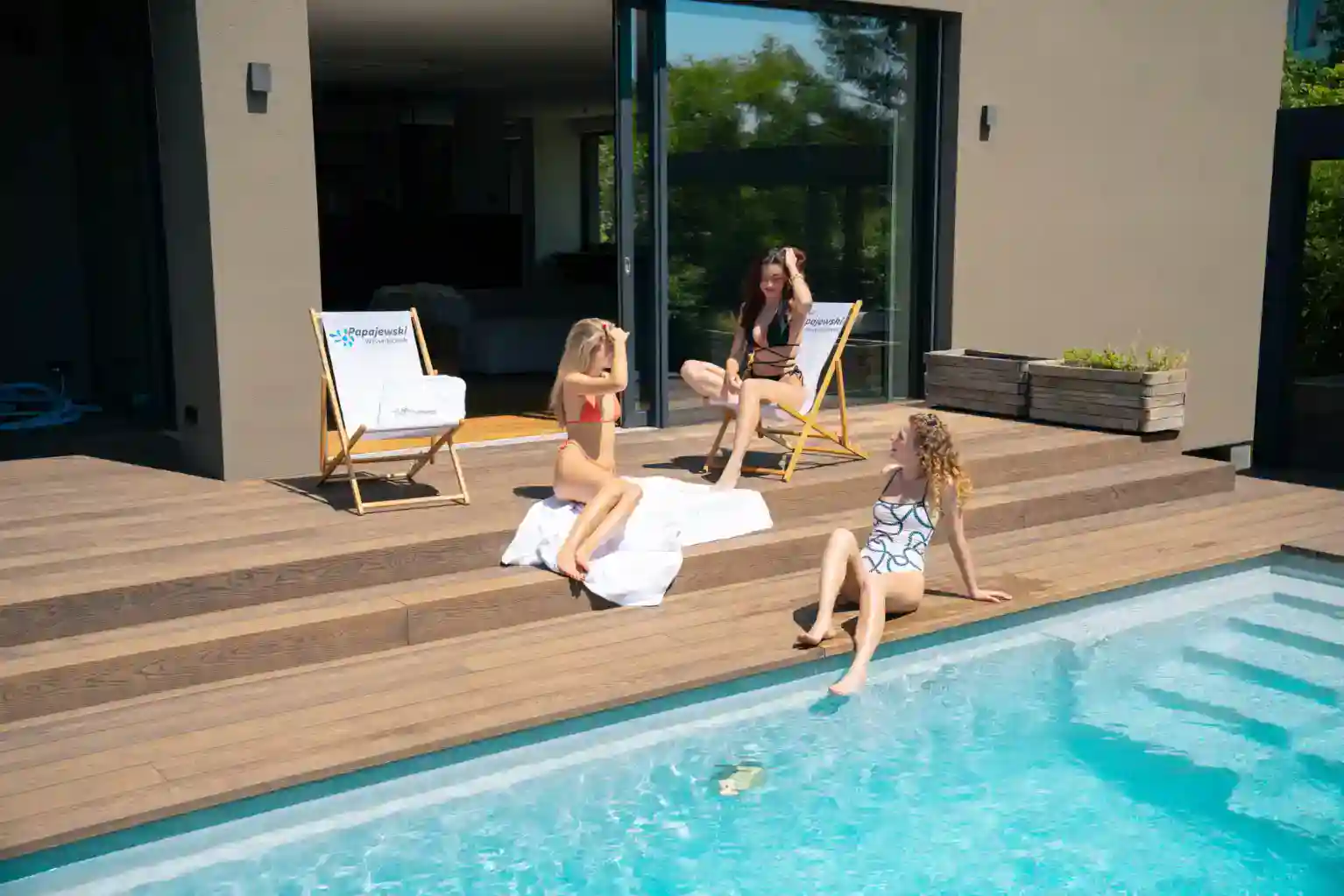 Drei Frauen auf einer Holzterasse neben einem individuellen Pool in der Nähe von Würzburg der von Papajewski gebaut wurde.