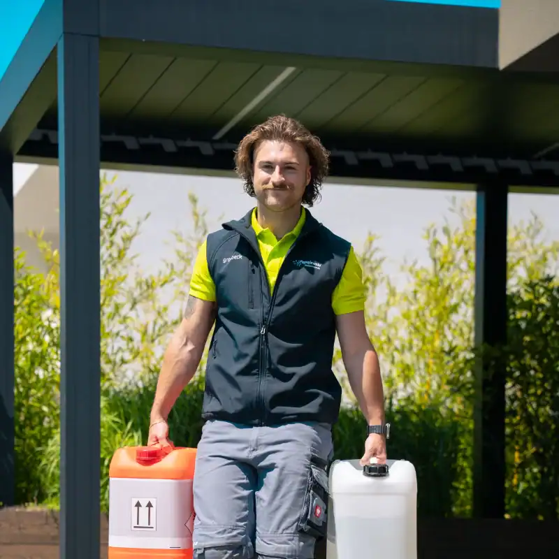 Hausmeister von Papajewski Poolbau und Wassertechnik trägt Kanister mit Poolpflegemitteln