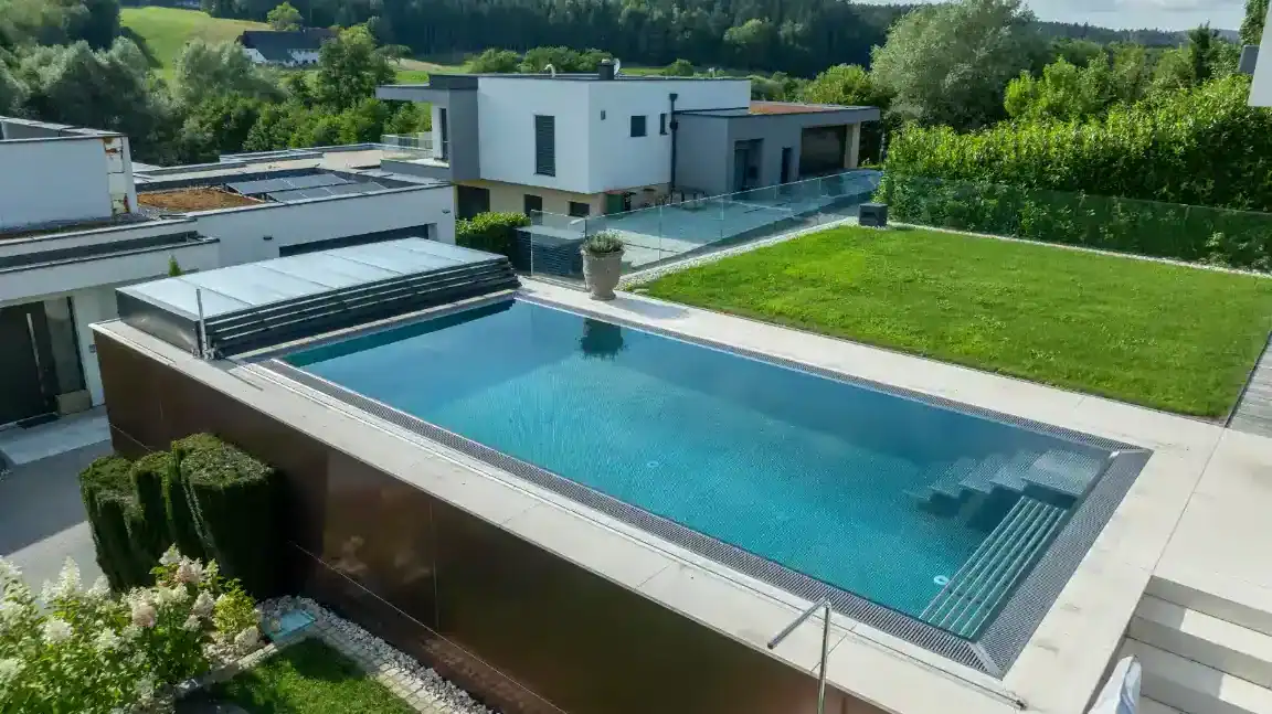 Rinnenpool aus Edelstahl von Papajewski Poolbau aus Würzburg neben einer Terrasse in einem Neubaugebiet.