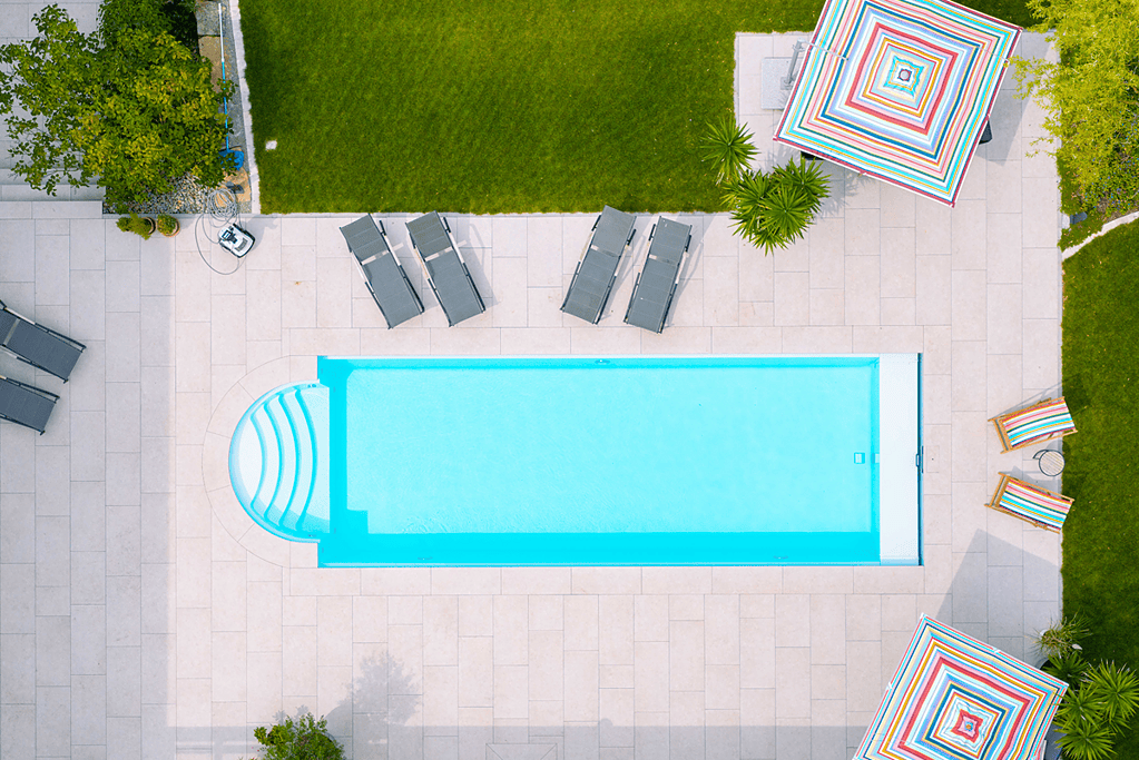 Fertig gebauter Pool mit Liegestühlen und gepflegter Gartenanlage aus der Vogelperspektive