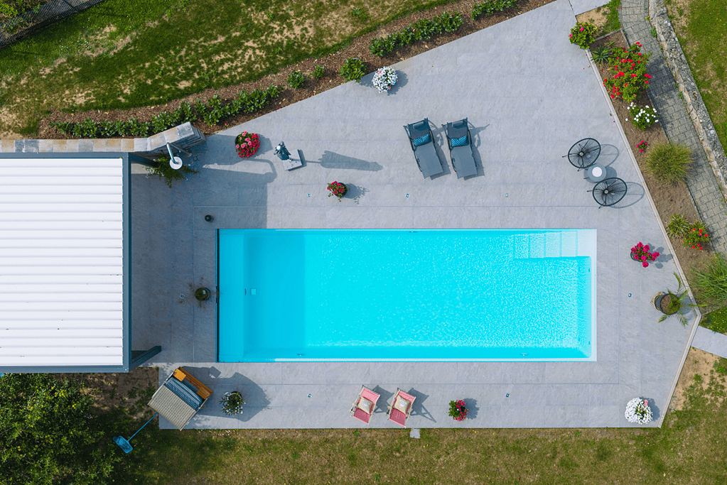 Poolbau Referenz aus der Vogelperspektive mit türkisblauem Rechteckpool im Hausgarten