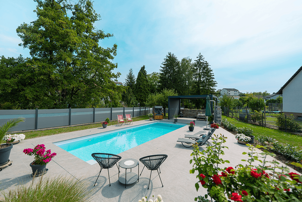 Poolbau Referenz mit Pool im Garten mit Loungemöbeln und blühenden Rosen im Vordergrund