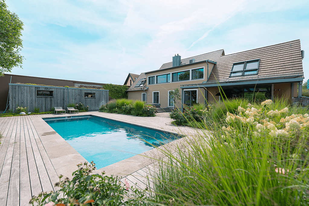Poolbau Referenz mit großzügigem Holzdeck direkt am modernen Wohnhaus