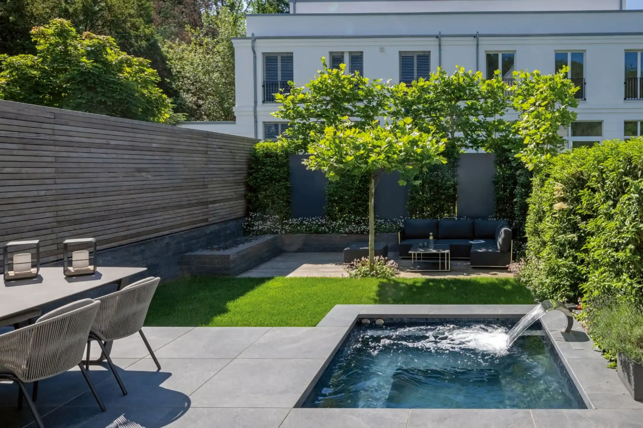 Minipool von CSIDE als Teil der Terrasse in einem kleinen Garten mit Gartenlounge im Hintergrund.